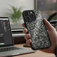 Person holding an iPhone with a carbon case in front of a laptop